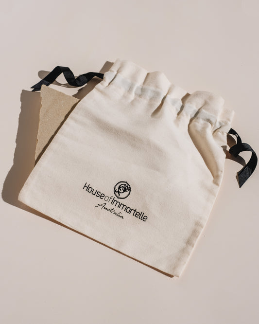 Elegant House of Immortelle Signature Cloth Bag made from premium fabric, featuring a sophisticated logo and sturdy handles, perfect for carrying luxury skincare products in style