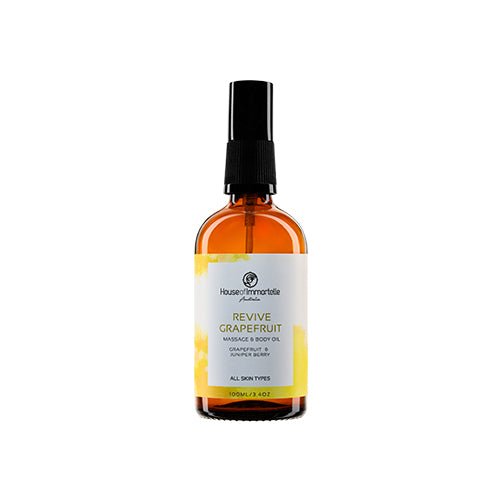 House of Immortelle Revive Grapefruit Massage Body Oil in a sleek bottle, infused with a refreshing grapefruit scent. The oil is designed to energize and revitalize the skin, with a smooth texture and invigorating fragrance, perfect for rejuvenating massages.